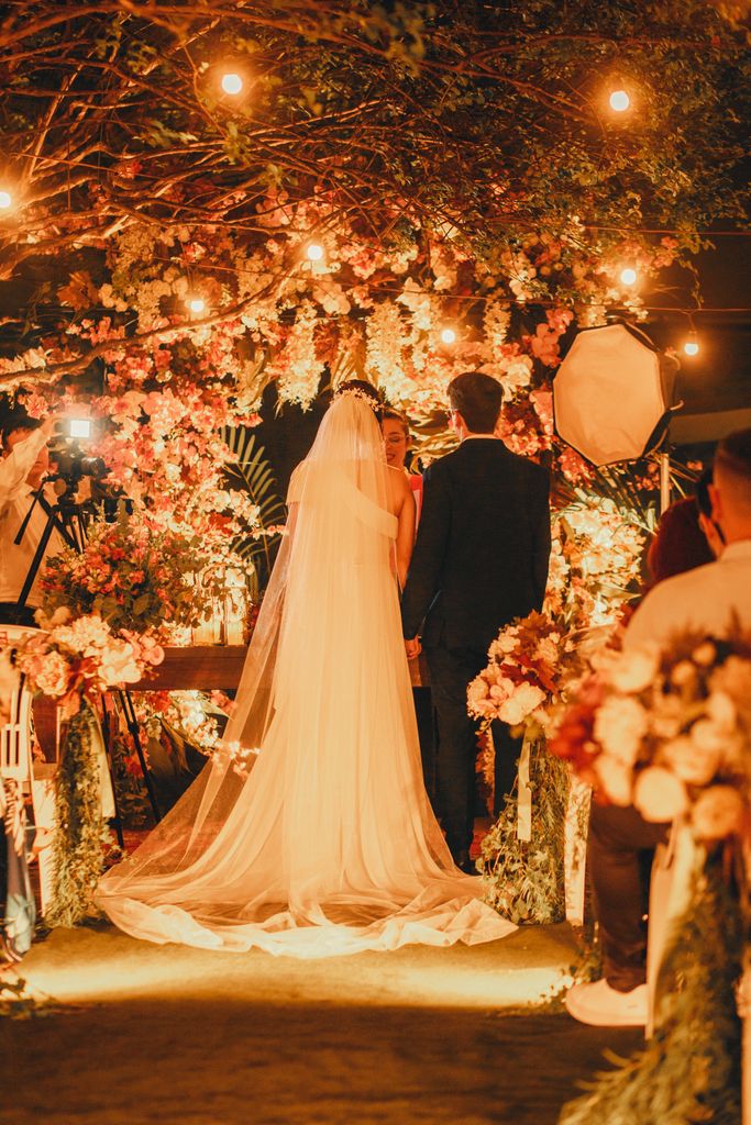 A beautifully illuminated outdoor wedding ceremony at night with bride and groom. contact.